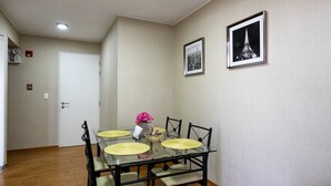 A dining area with a glass table, black chairs, and a white door in the background. - UR Place Rentals - 3Bdrm Av Brasil Lima (Lima)