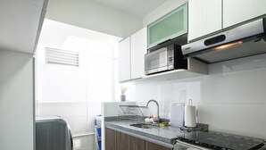 A compact kitchen with a built-in microwave, stove, and sink. - UR Place Rentals - 3Bdrm Av Brasil Lima (Lima)