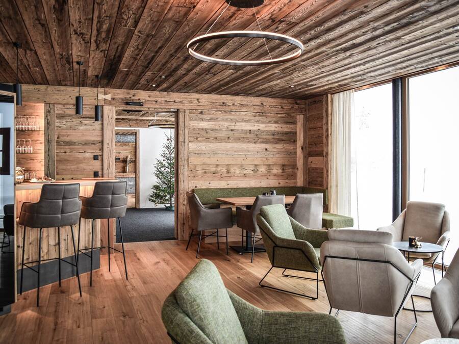 Un interior moderno con paredes de madera, una zona de bar y diferentes disposiciones de asientos.