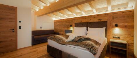 A modern bedroom with a wooden ceiling, a large bed, a nightstand, and a built-in bench.