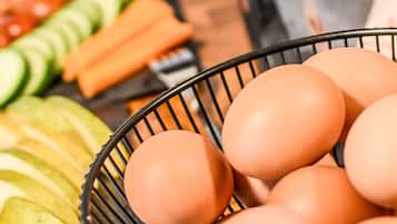 A kitchen counter with a basket of eggs, sliced cucumbers, carrots, and apples.
