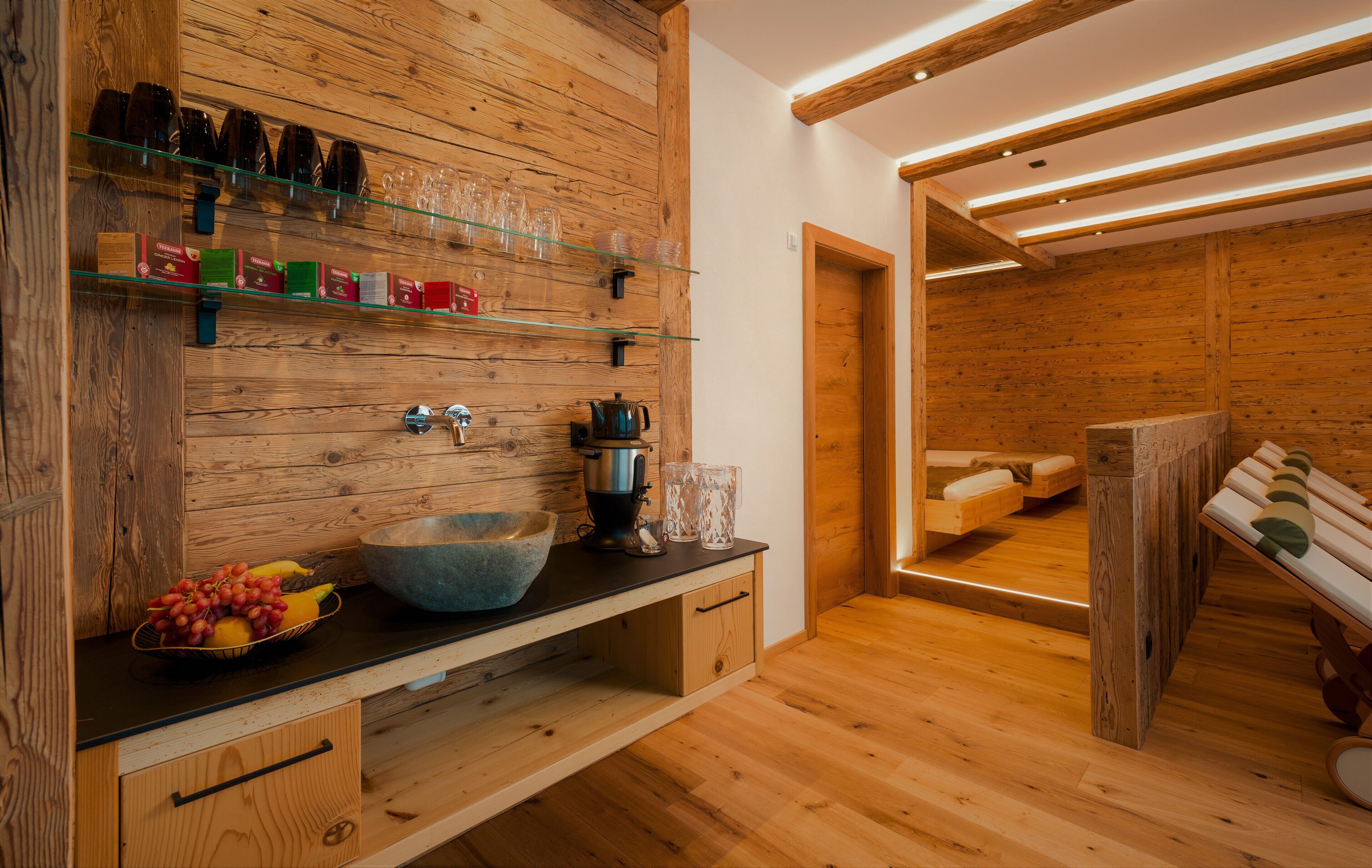 Un interior de madera con un lavabo de piedra grande, estantes de vidrio y un banco.