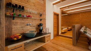 Un interior de madera con un lavabo de piedra grande, estantes de vidrio y un banco.