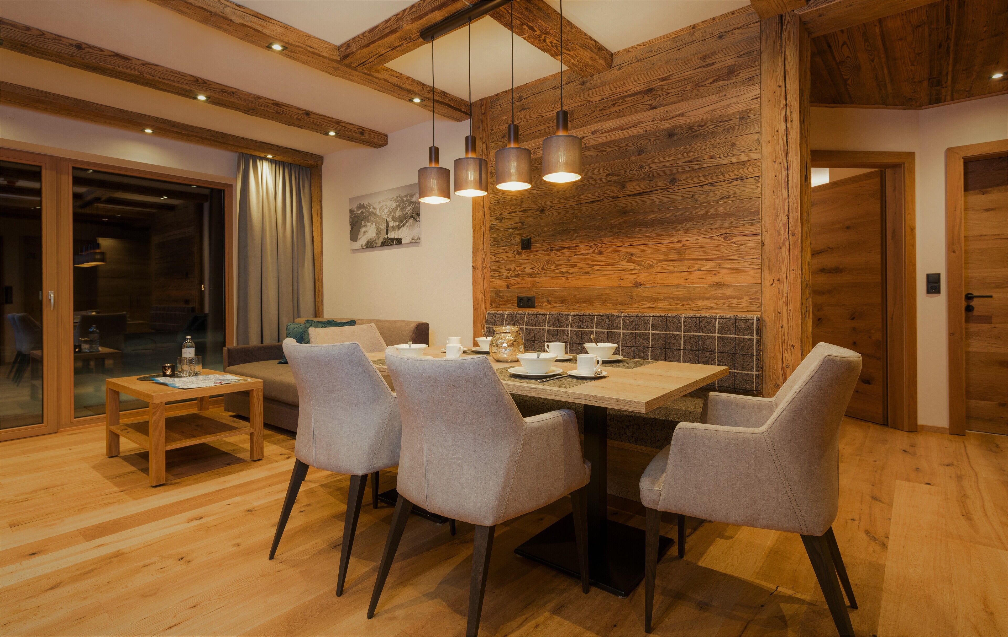 Ein Essbereich mit einem Holztisch, vier Stühlen und hängenden Pendelleuchten.