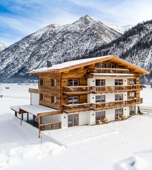 Una cabaña de madera de varios pisos con balcones, ubicada en una zona montañosa nevada.