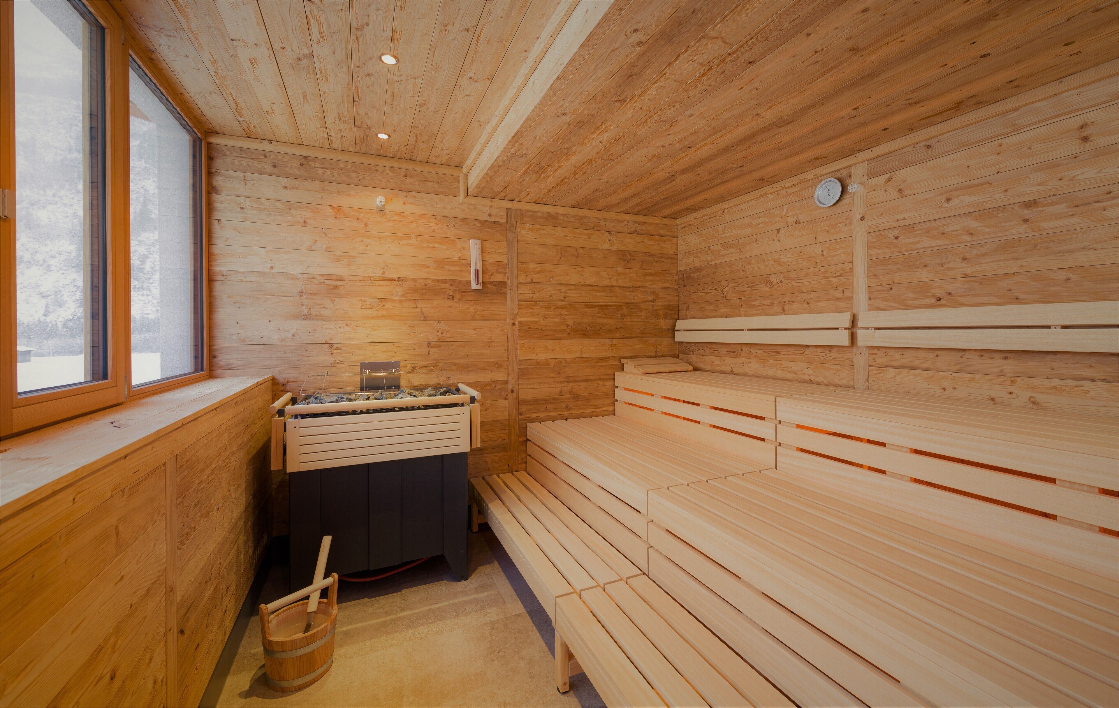 Un cuarto de sauna con bancos de madera, un calentador para los bancos y una ventana.