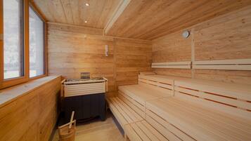 Un cuarto de sauna con bancos de madera, un calentador para los bancos y una ventana.