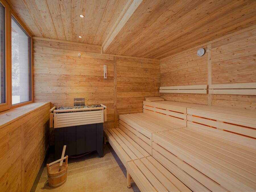 Un cuarto de sauna con bancos de madera, un calentador para los bancos y una ventana.