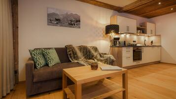 A cozy living area with a sofa, a coffee table, and a kitchen in the background.