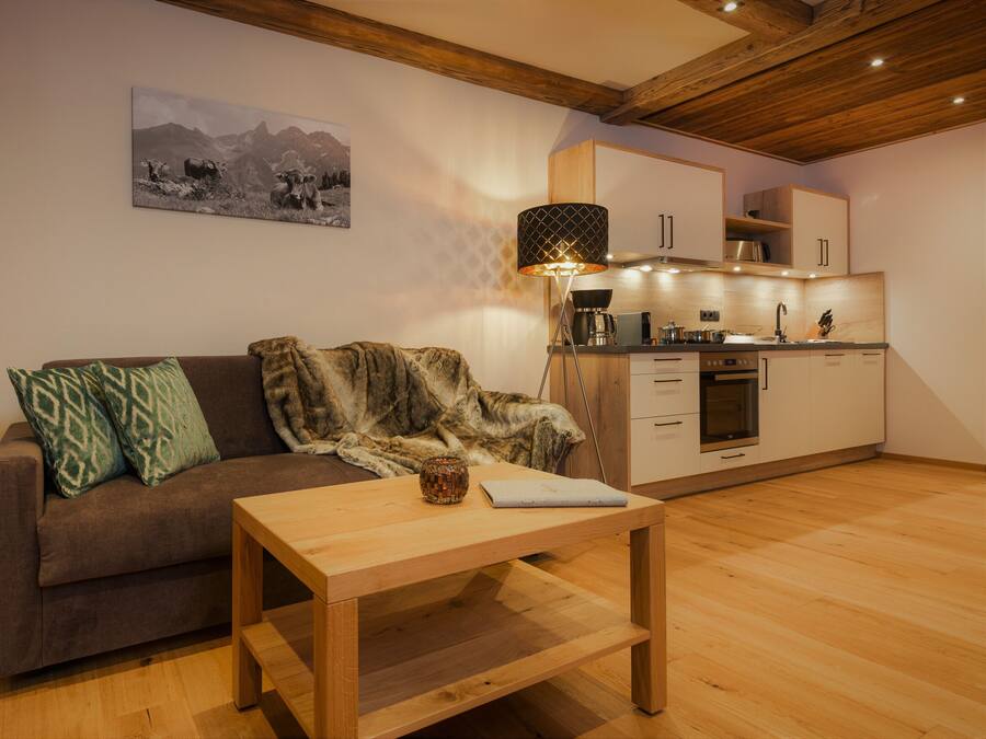 A cozy living area with a sofa, a coffee table, and a kitchen in the background.