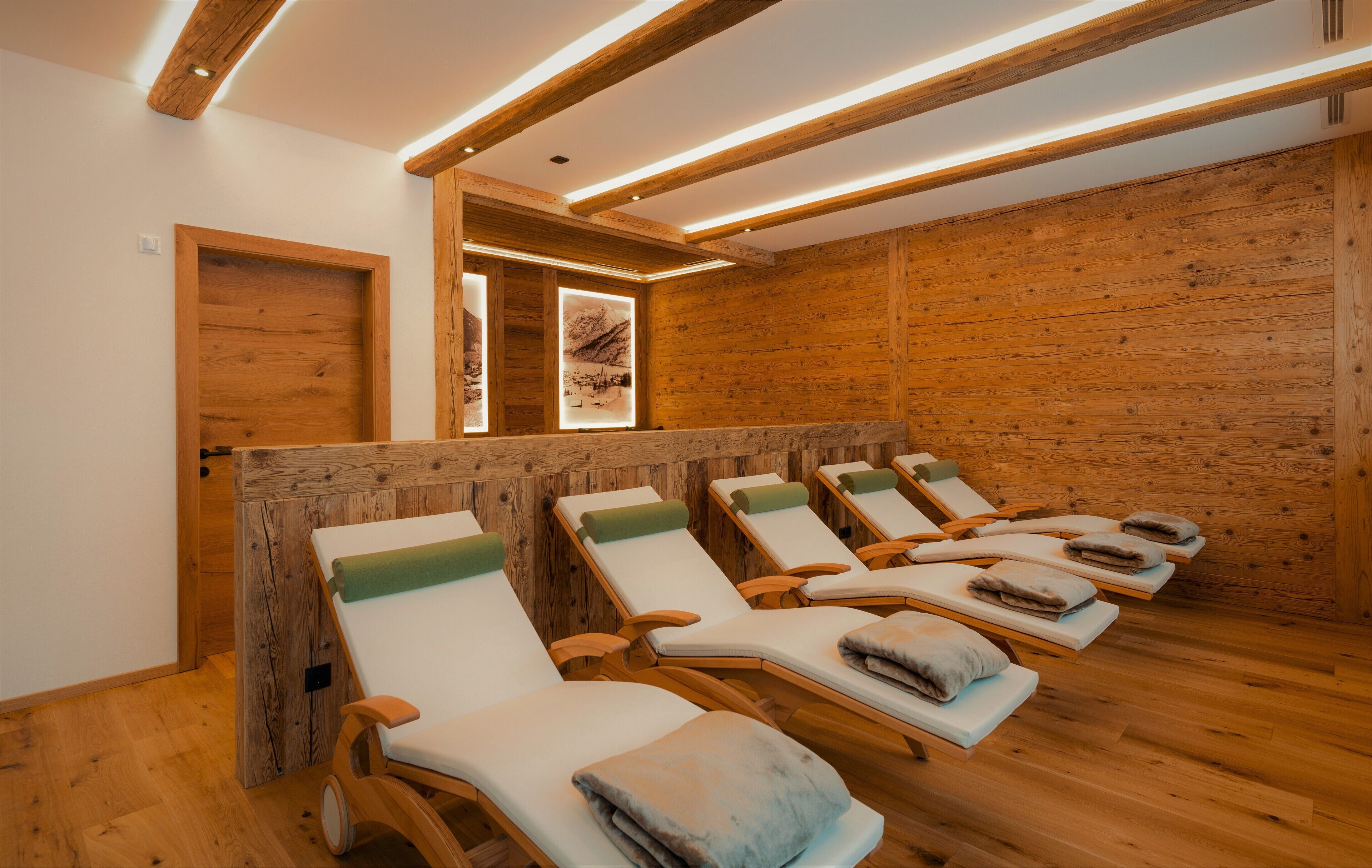 A room with wooden walls and ceiling, equipped with multiple sun loungers and a wooden door.