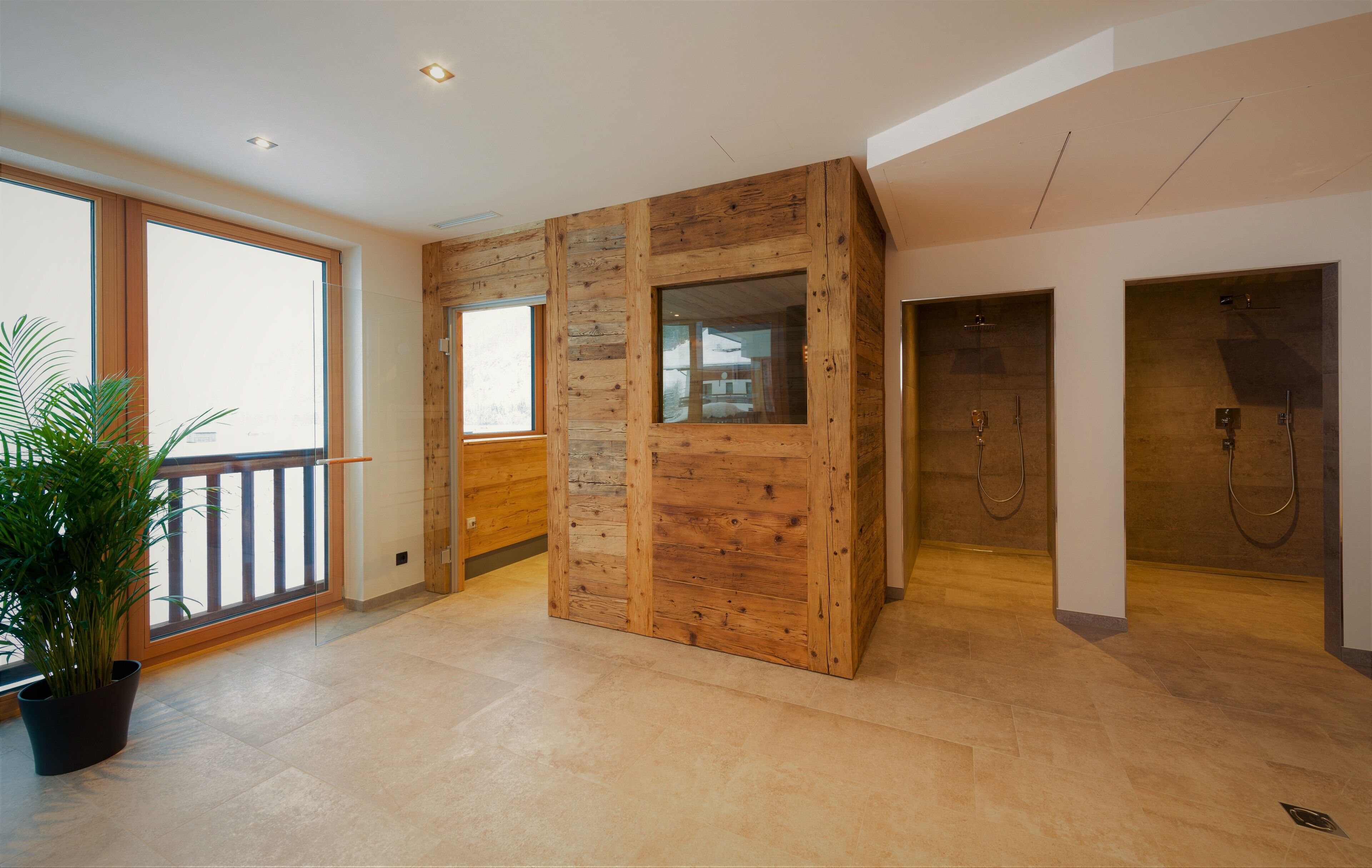 Una habitación espaciosa con un gran ventanal, paneles de madera y una planta en maceta.