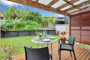 A covered patio with a round table, two chairs, and a variety of plants.