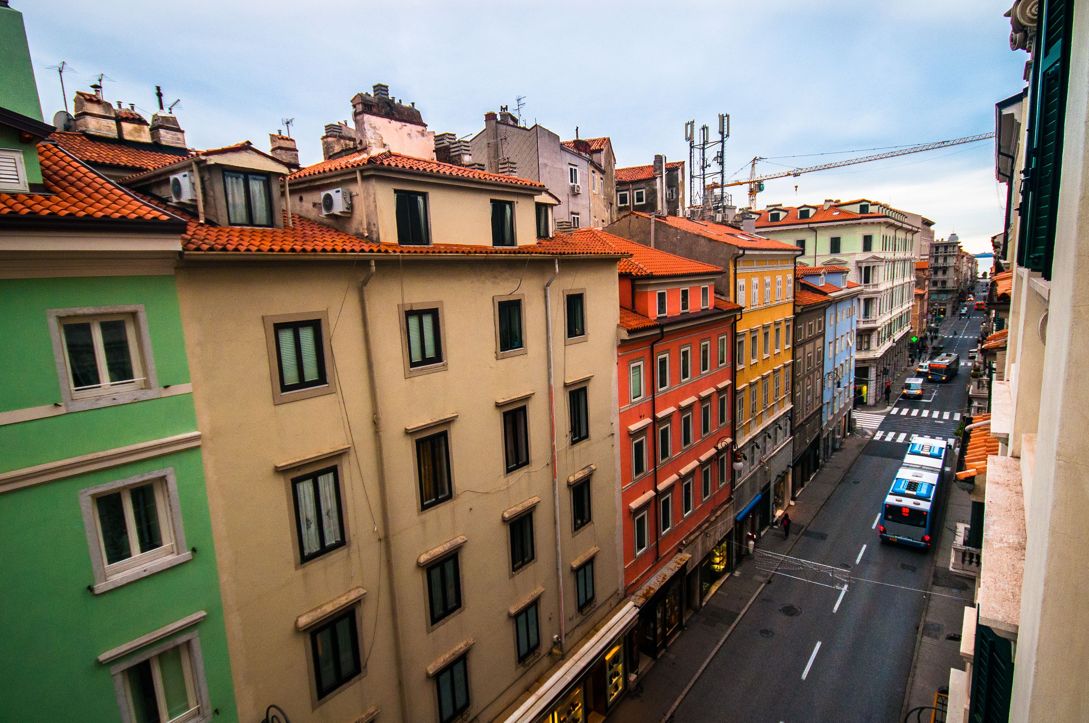 Une vue de rue d’une ville avec des immeubles à plusieurs étages, une route dégagée et un autobus.
