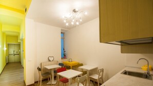 A compact kitchen with a sink, a dining area with chairs and a table, and a hallway leading to another room. - B&B Dream Center (Trieste)
