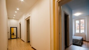 A hallway with wooden flooring, white walls, and a bed in the adjacent room. - B&B Dream Center (Trieste)