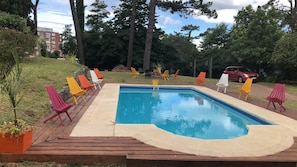 Una piscina al aire libre de temporada, sillones reclinables de piscina