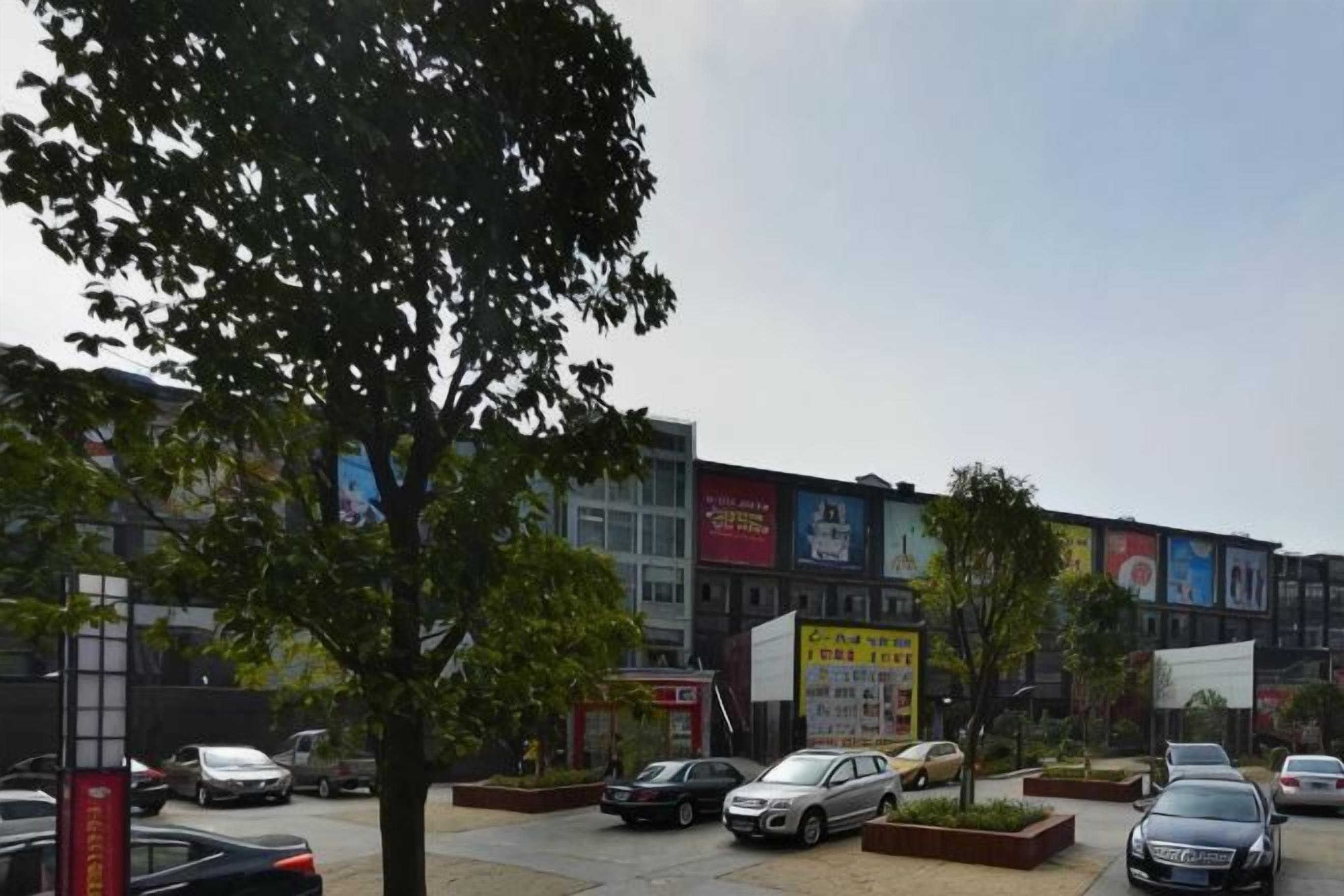 Un estacionamiento con varios autos y un edificio con diferentes letreros y banderolas.