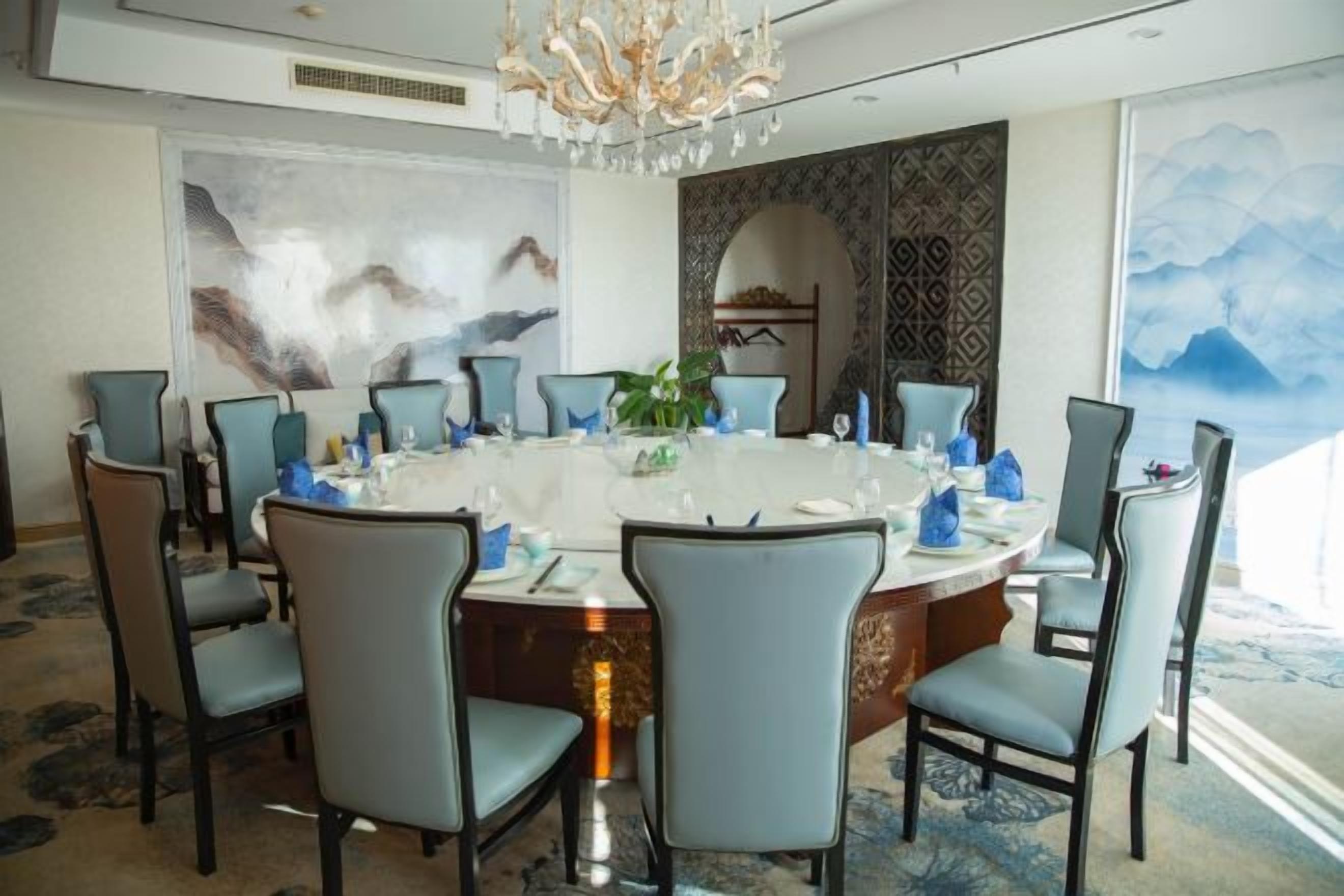 A dining area with a round table, chairs, and a chandelier.