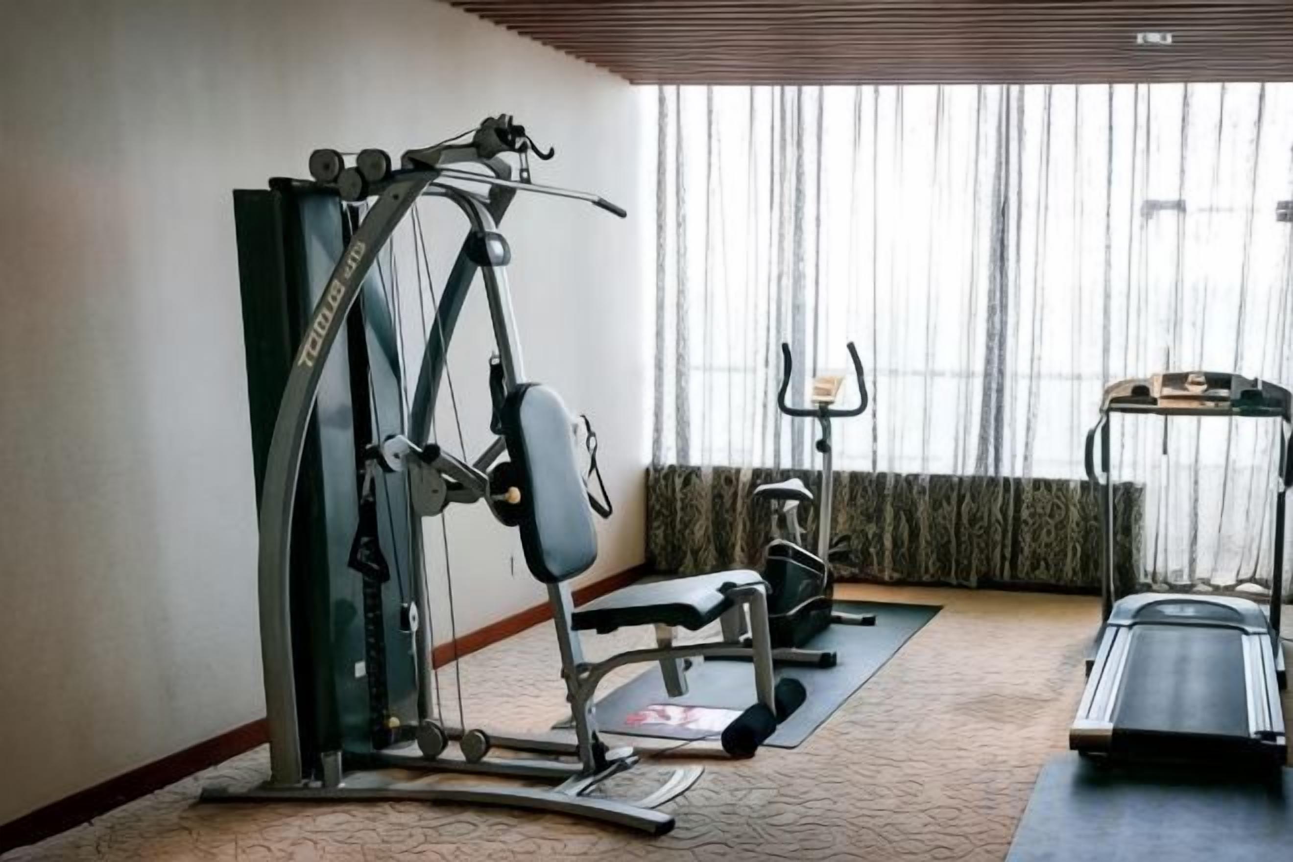 A gym with exercise equipment including a treadmill, stationary bike, and weight machines.