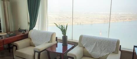 A room with two sofas, a small table, and a view of a body of water.
