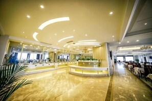A spacious lobby with a central reception desk, a curved ceiling with recessed lighting, and a long corridor leading to a dining area. - Sizhou Hotel (Xuyi)