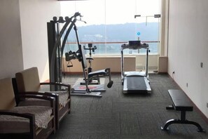 A hotel room with a bed, a treadmill, a bench, and a window with a view of mountains. - Sizhou Hotel (Xuyi)