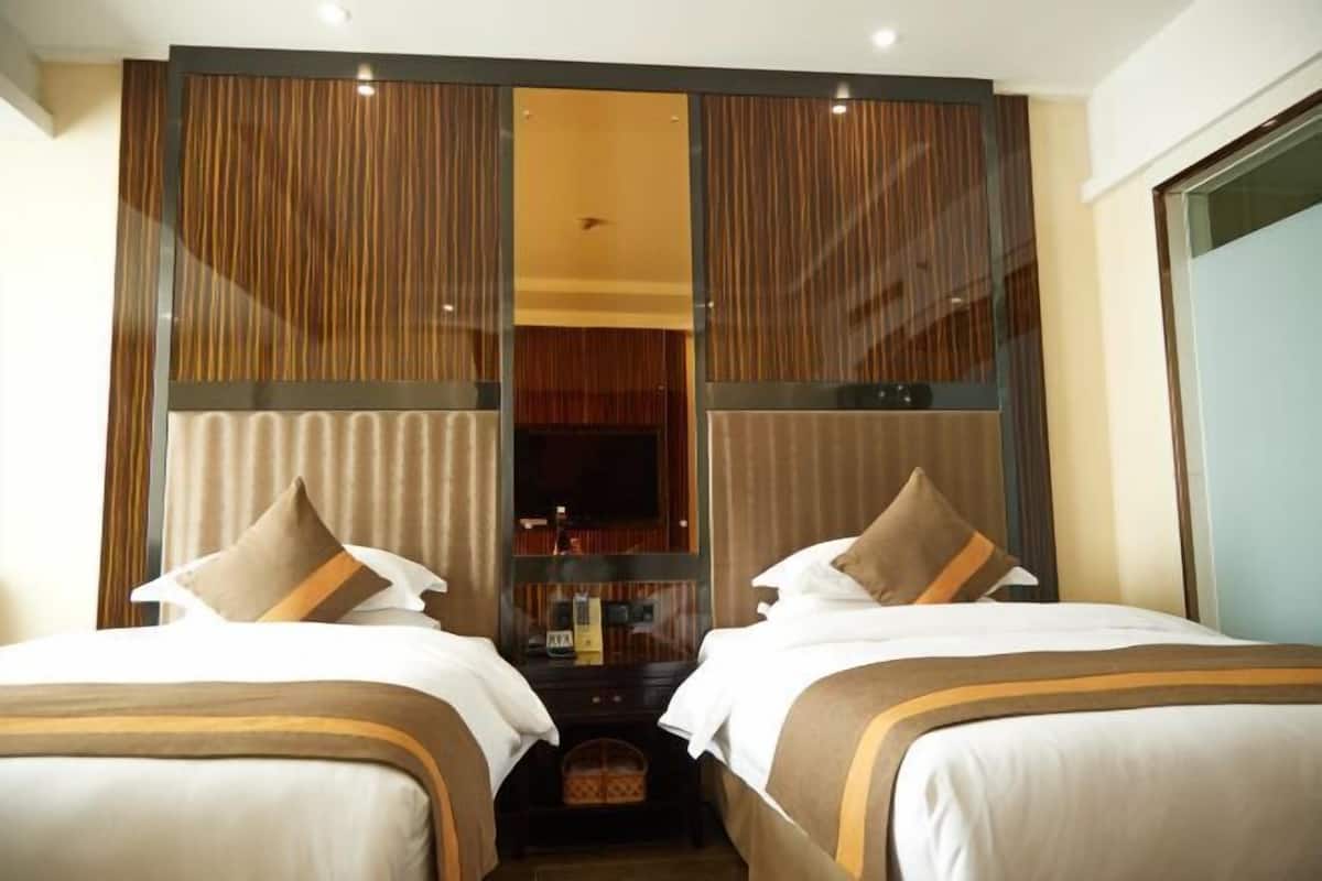 A hotel room with two beds, a television, and a minibar.