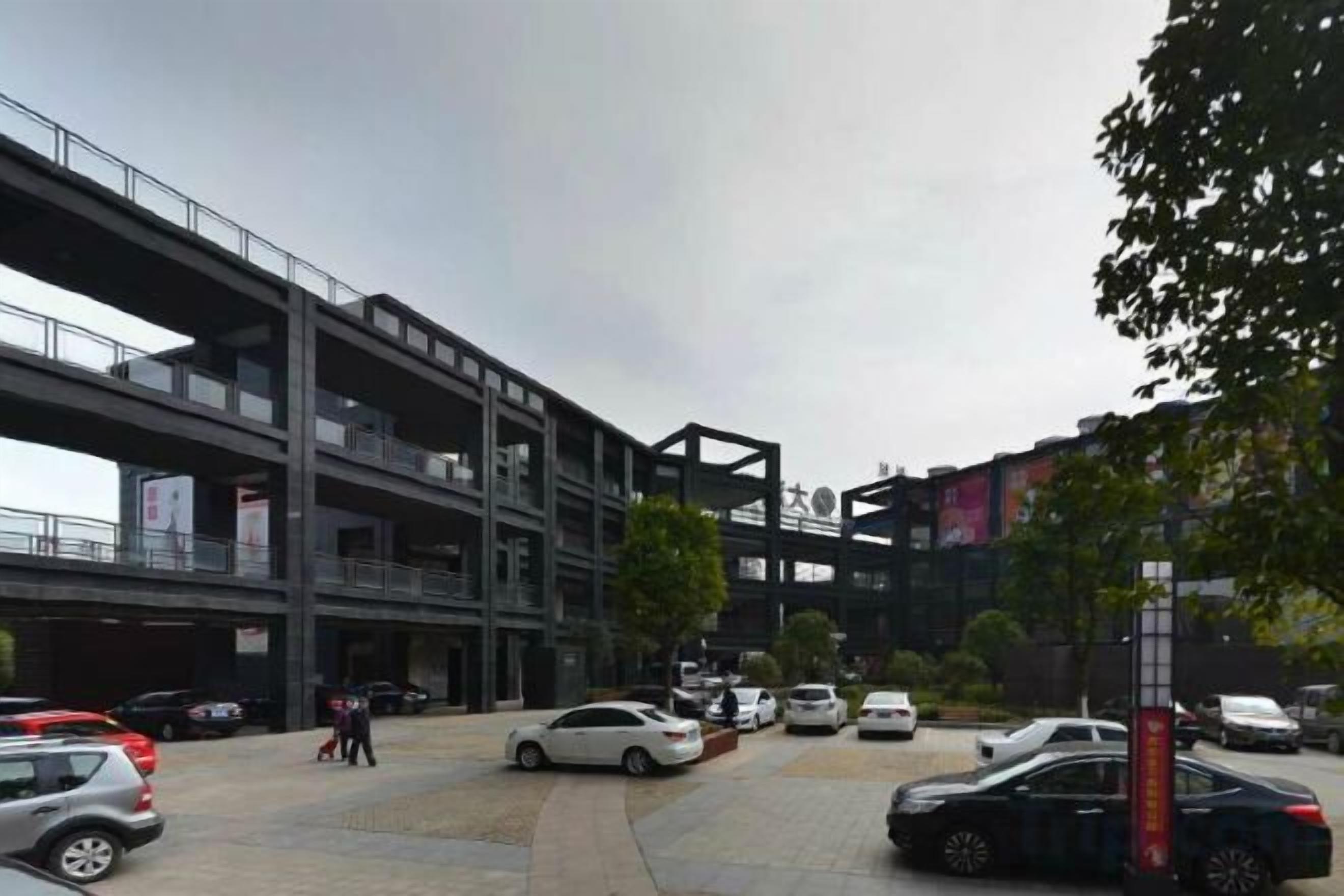 A multi-story parking structure with cars parked on the ground level.