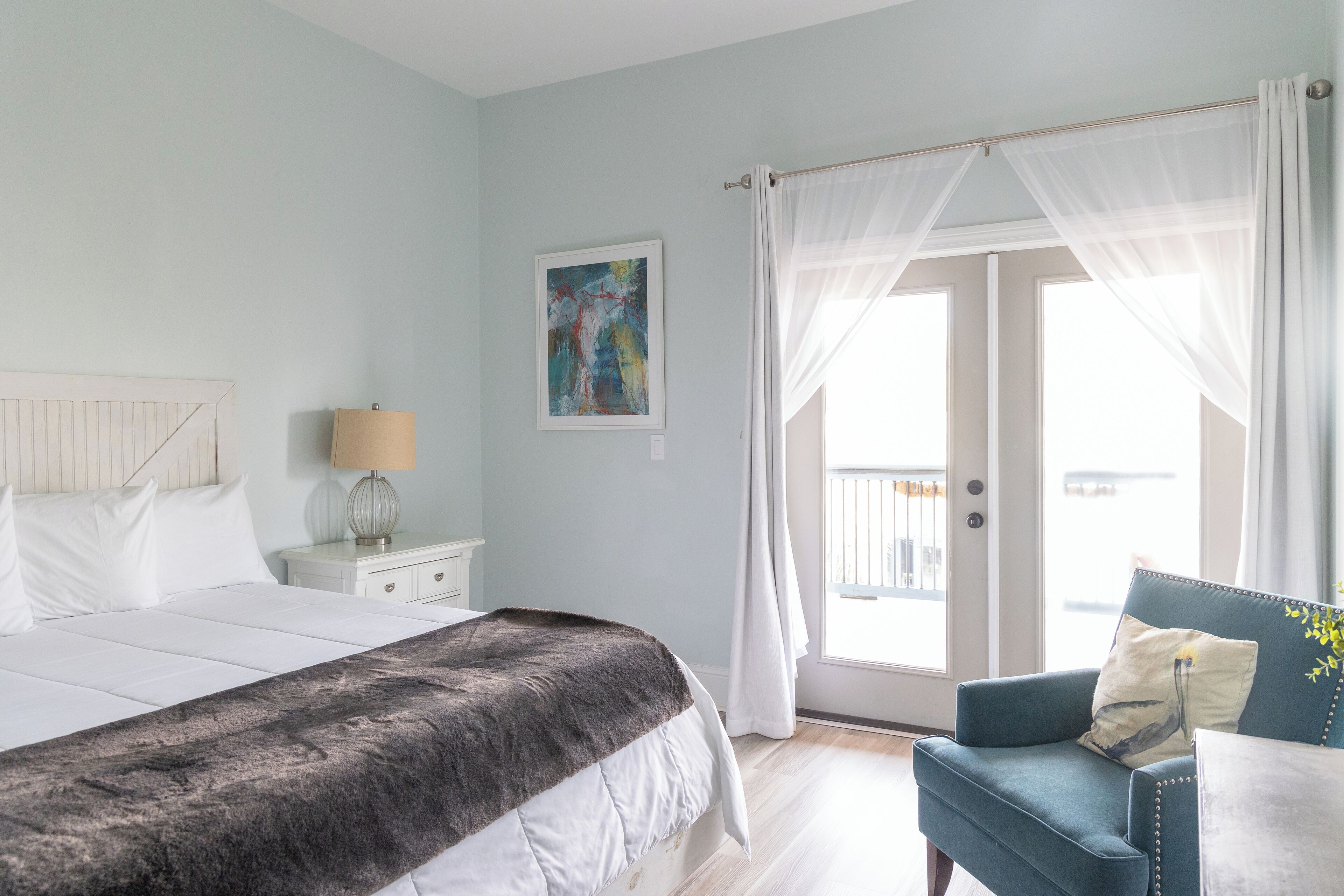 A bedroom with a bed, a nightstand, a chair, and a window with curtains.