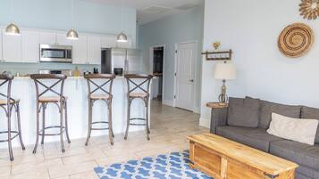 A modern kitchen with white cabinets, stainless steel appliances, and a bar area with stools.