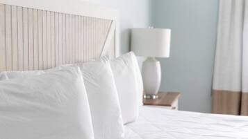 A neatly made bed with white linens and a wooden headboard.