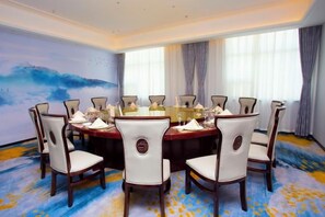 A conference room with a round table, eight chairs, and a large window with curtains. - Yeshi International Hotel (Shuyang)