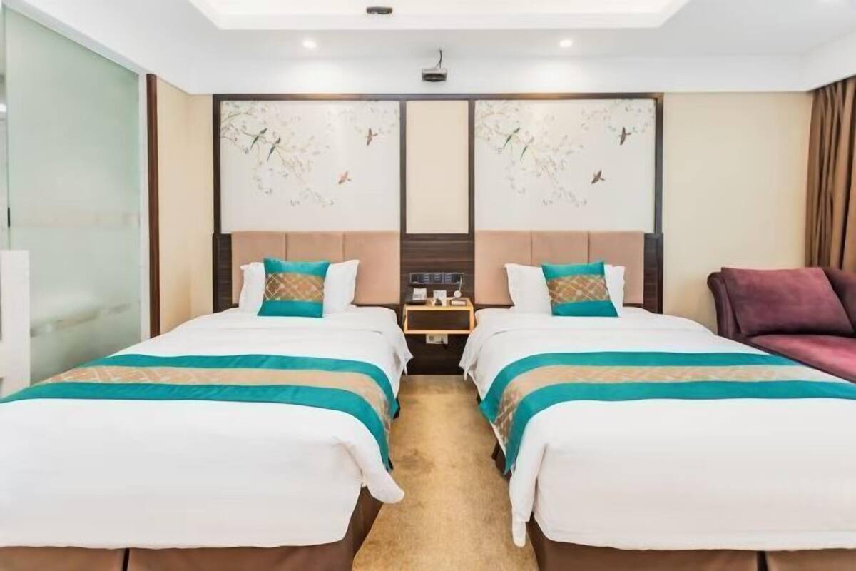 A hotel room with two beds, a nightstand, and a large window.