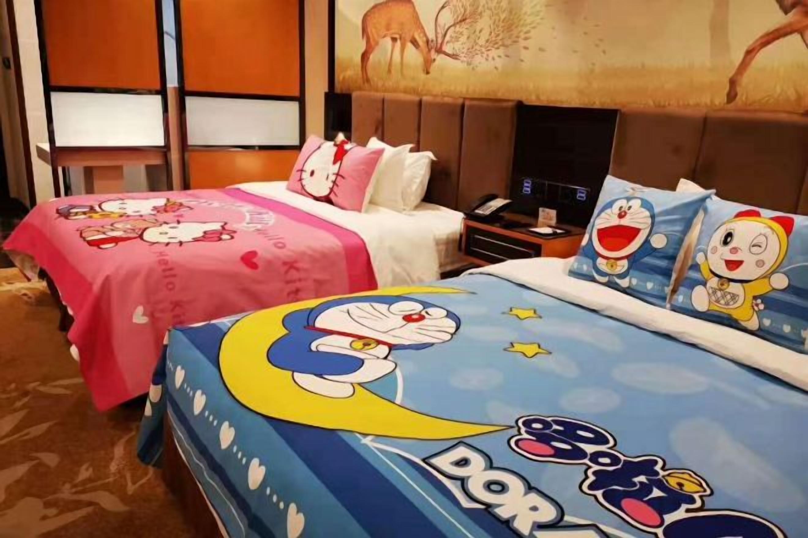 A hotel room with two beds, each with themed bedding, a nightstand, and a television.