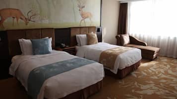 A hotel room with two beds, a sofa, a large painting of deer, and a view of the outdoors.