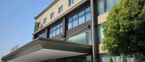 Un hotel con fachada moderna, amplias ventanas y entrada cubierta.