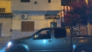 A building with a sign that reads "AMANECERES H" and a parked vehicle in front.