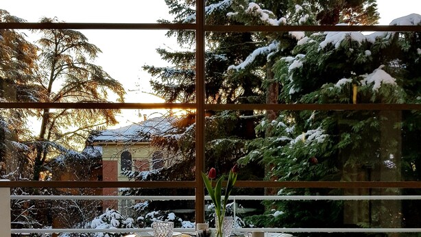 A dining area with a table set for four, chairs, and a vase with flowers. - Villa Gotti Charming Rooms (Bologna)