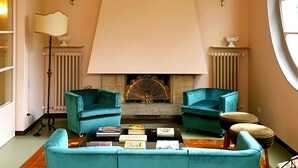 A living room with a large sofa, a fireplace, and a window. - Villa Gotti Charming Rooms (Bologna)