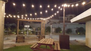 An outdoor patio area with string lights, wooden furniture, and a pergola. - 5615 Properties (Las Vegas)