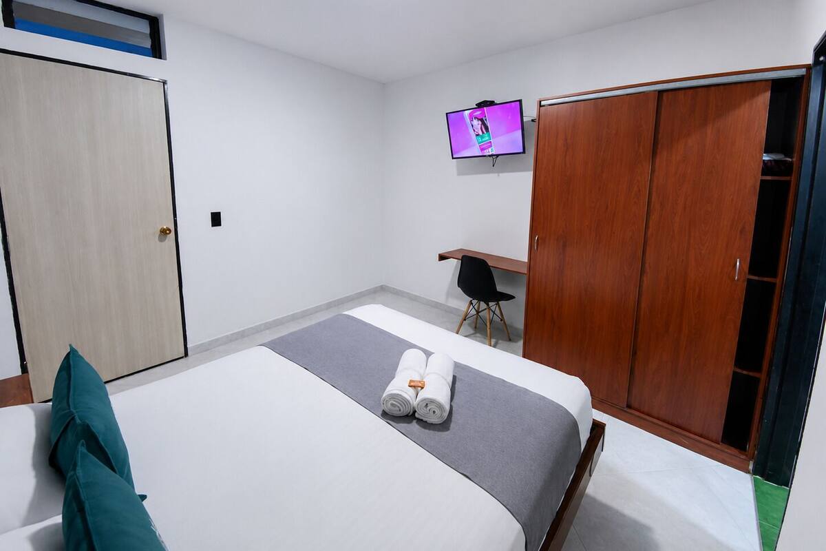 Ein Hotelzimmer mit Bett, Schreibtisch, Fernseher und Kleiderschrank.