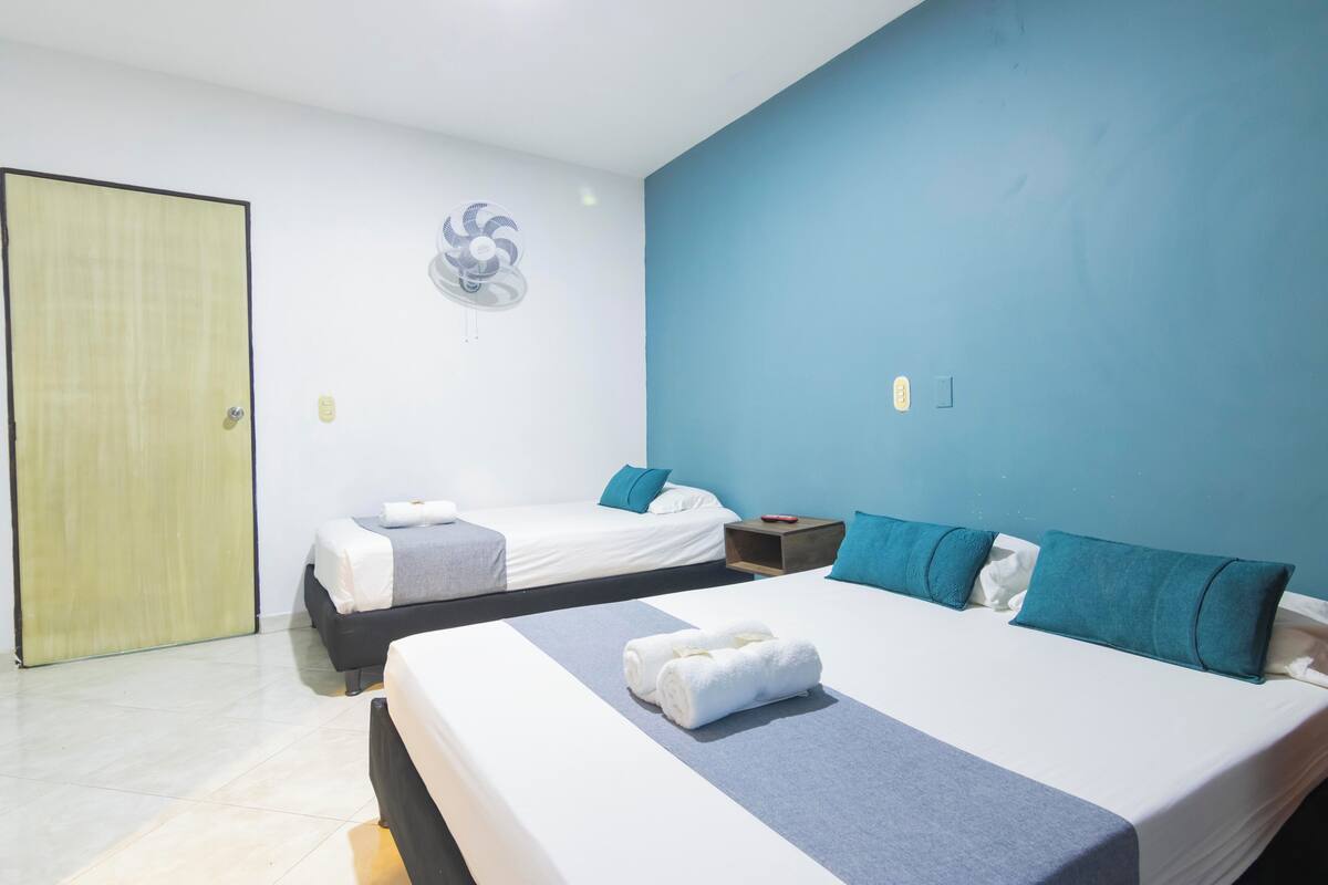 Ein Hotelzimmer mit zwei Betten, einem Deckenventilator und einer Tür.