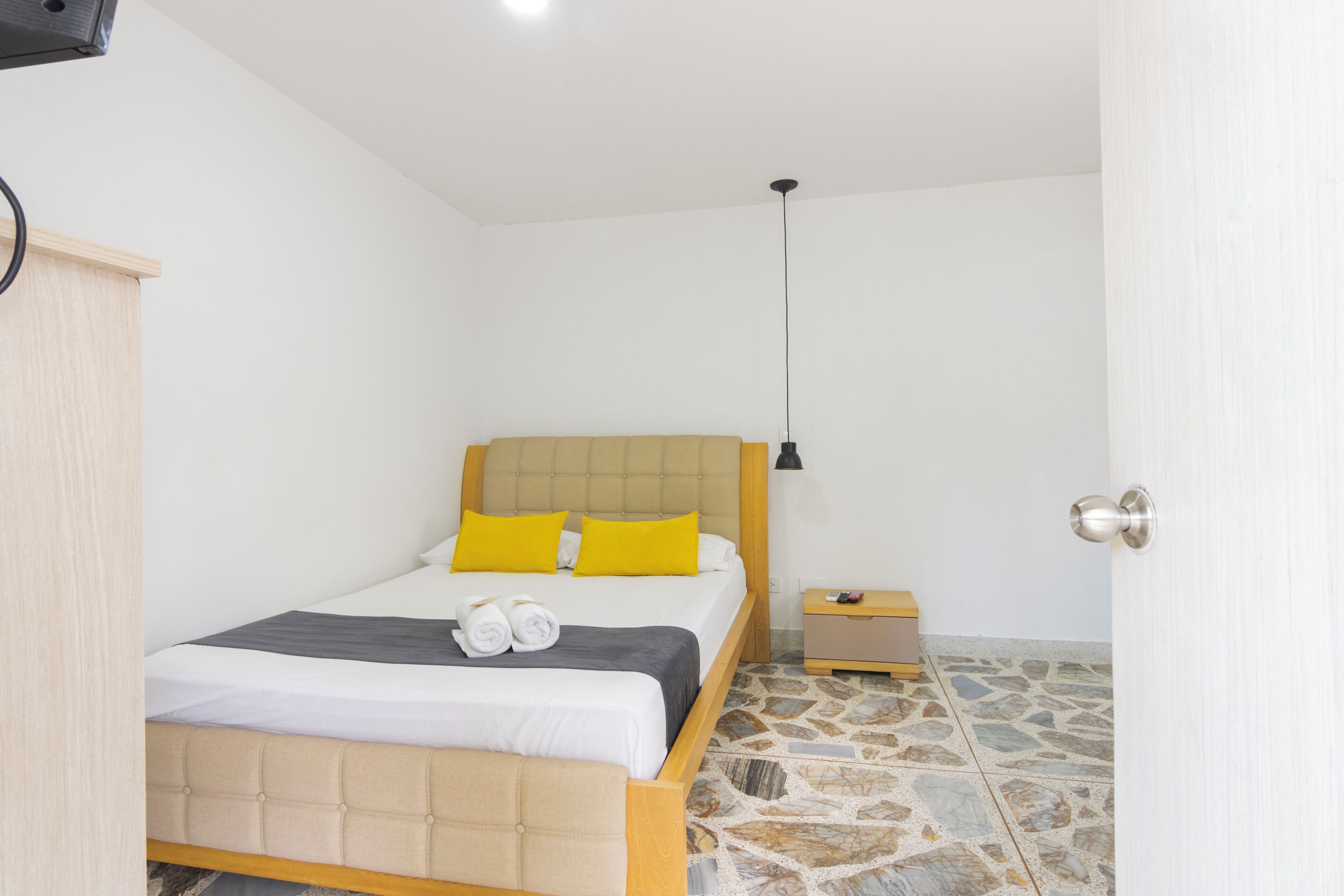 Un dormitorio con cama, mesita de noche, lámpara y puerta.