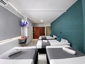A hotel room with three beds, a desk, a TV, and a wardrobe. - Hotel Balcones de la 70 (Medellín)