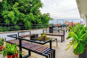 Terraza en la azotea con mobiliario exterior, plantas en macetas y vistas de la ciudad.