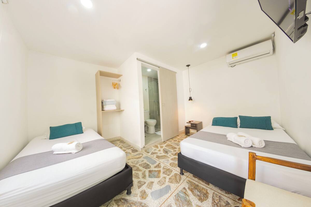 Ein Hotelzimmer mit zwei Betten, einem Badezimmer und einem kleinen Tisch.