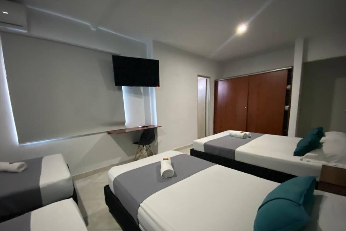 Ein Hotelzimmer mit zwei Betten, einem Fernseher, einem Kleiderschrank und einem Schreibtisch mit Stuhl.