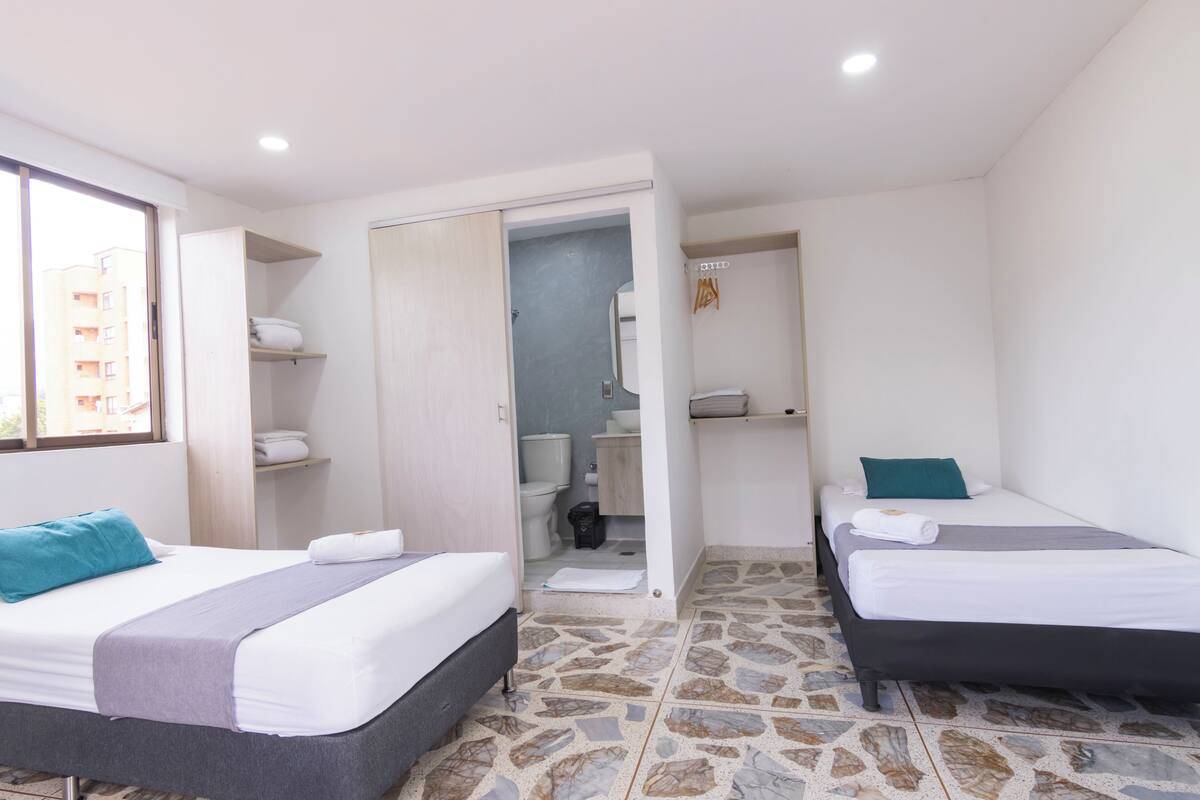 Ein Hotelzimmer mit zwei Betten, einem Badezimmer und Blick ins Freie.