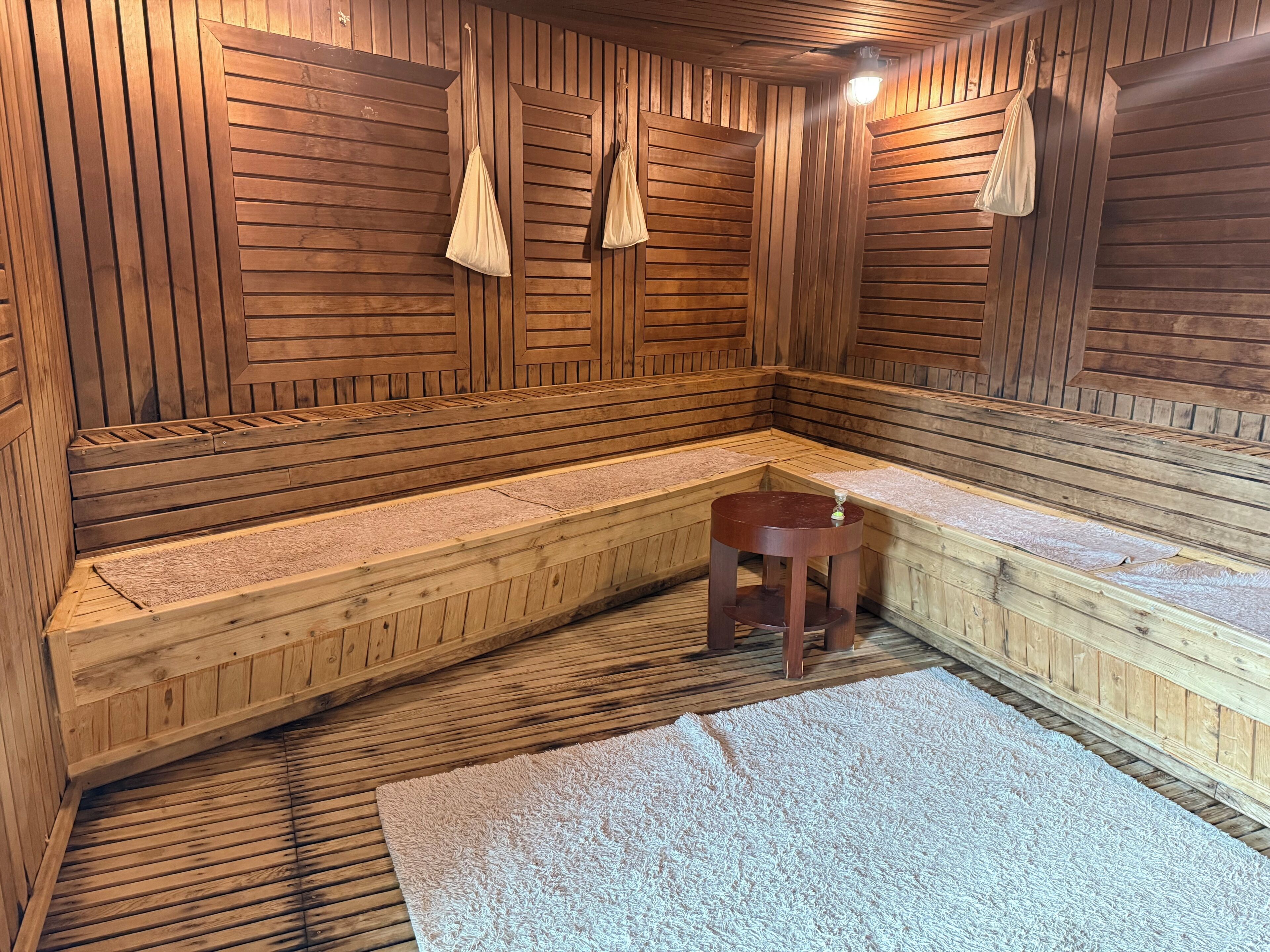 Una sauna con bancos de madera, un taburete pequeño y toallas.